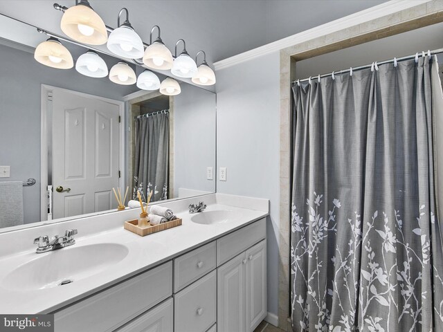 full bath with a sink, double vanity, and crown molding