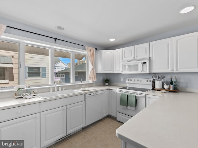 kitchen featuring white appliances, white cabinets, recessed lighting, and a sink