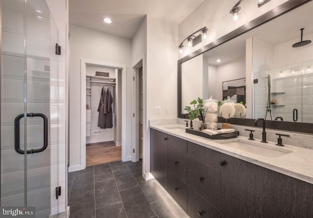 full bathroom featuring a sink, a spacious closet, a stall shower, and double vanity