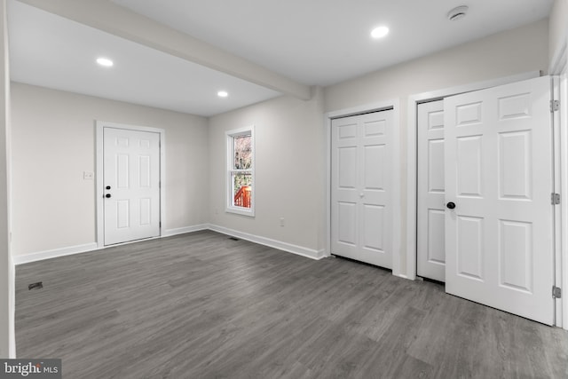 unfurnished bedroom with dark wood-style floors, recessed lighting, baseboards, and multiple closets