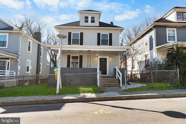 american foursquare style home featuring a fenced front yard, covered porch, and a front lawn