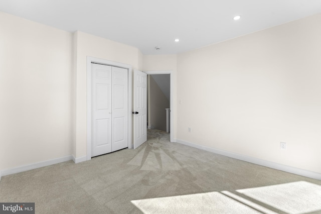 unfurnished bedroom featuring recessed lighting, baseboards, a closet, and light carpet