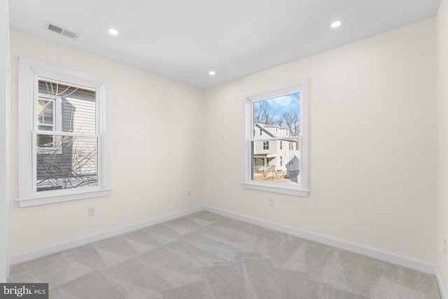 unfurnished room featuring light carpet, visible vents, a healthy amount of sunlight, and baseboards