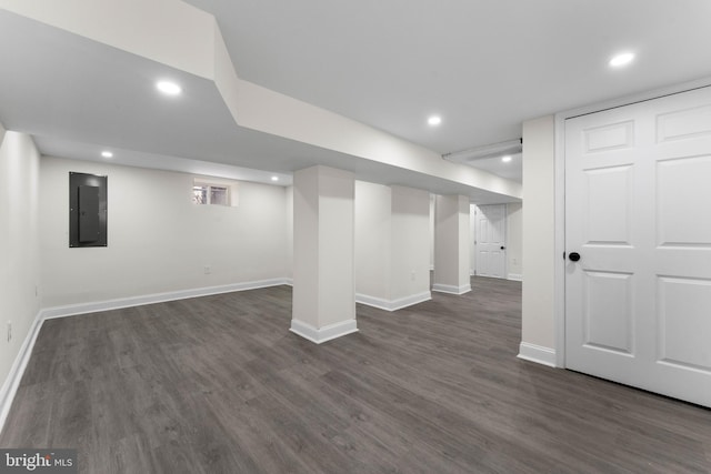 finished basement featuring electric panel, dark wood-style floors, recessed lighting, and baseboards