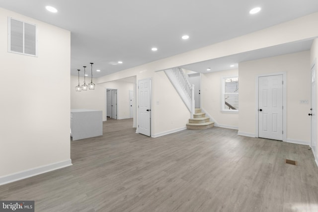 unfurnished living room with recessed lighting, visible vents, stairs, and light wood finished floors