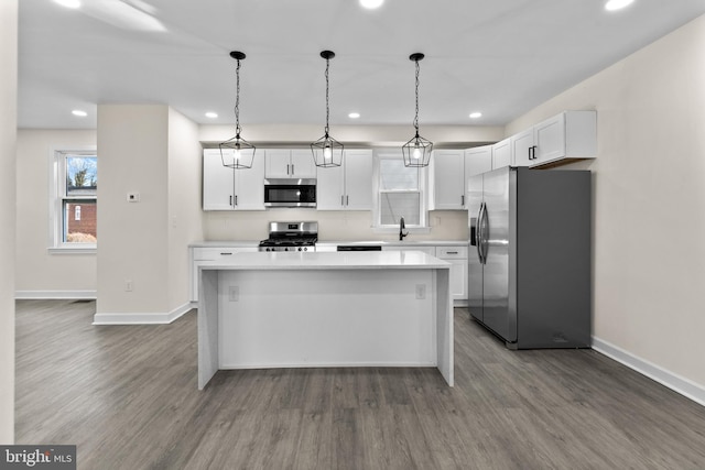 kitchen featuring dark wood-type flooring, a center island, appliances with stainless steel finishes, and a sink