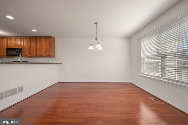 unfurnished dining area featuring visible vents, baseboards, a chandelier, recessed lighting, and wood finished floors