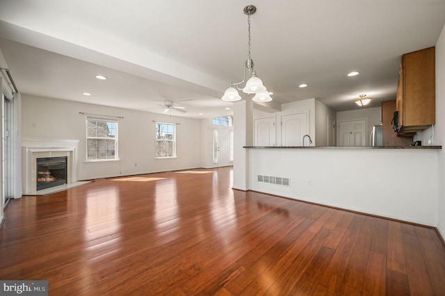 unfurnished living room featuring recessed lighting, visible vents, dark wood-style floors, and a high end fireplace