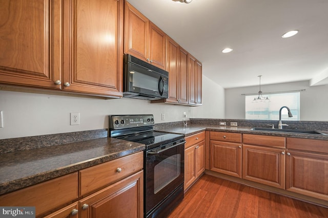 kitchen featuring brown cabinets, black appliances, a sink, dark wood-style floors, and recessed lighting