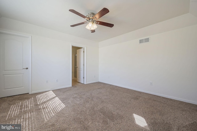 carpeted empty room featuring visible vents, a ceiling fan, and baseboards