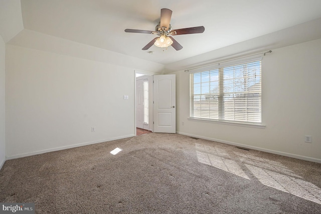 carpeted spare room with visible vents, ceiling fan, and baseboards