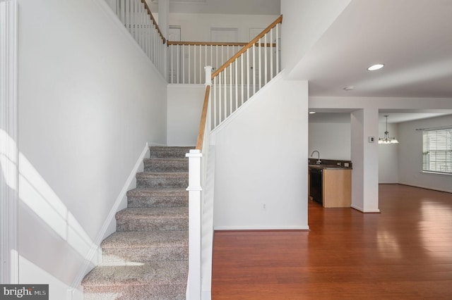 stairway with recessed lighting, baseboards, an inviting chandelier, and wood finished floors