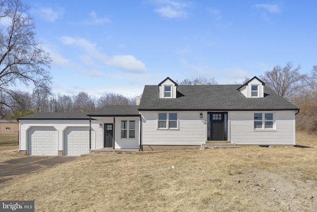 new england style home with a front lawn, a garage, driveway, and roof with shingles