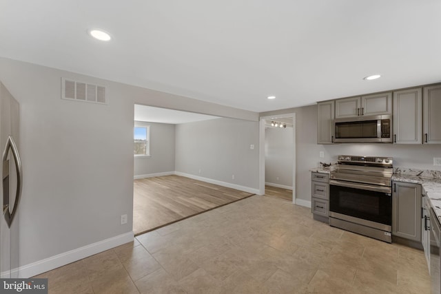 kitchen featuring stainless steel appliances, baseboards, visible vents, and gray cabinets