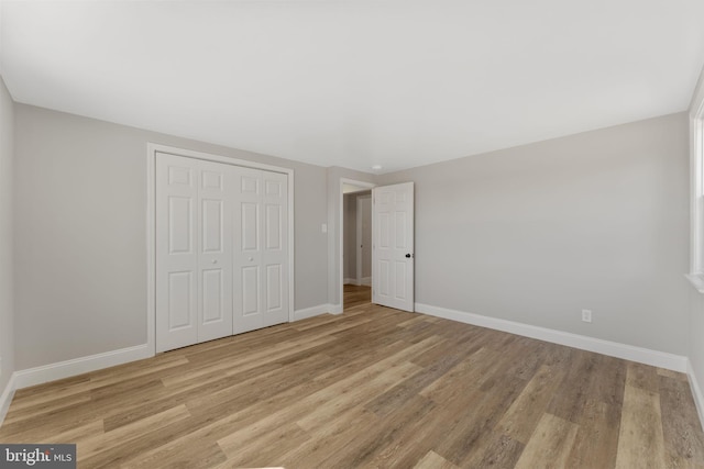 unfurnished bedroom with a closet, baseboards, and wood finished floors