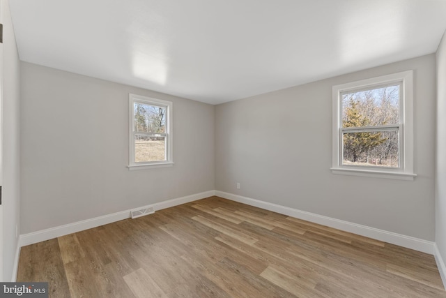 unfurnished room with visible vents, baseboards, and wood finished floors