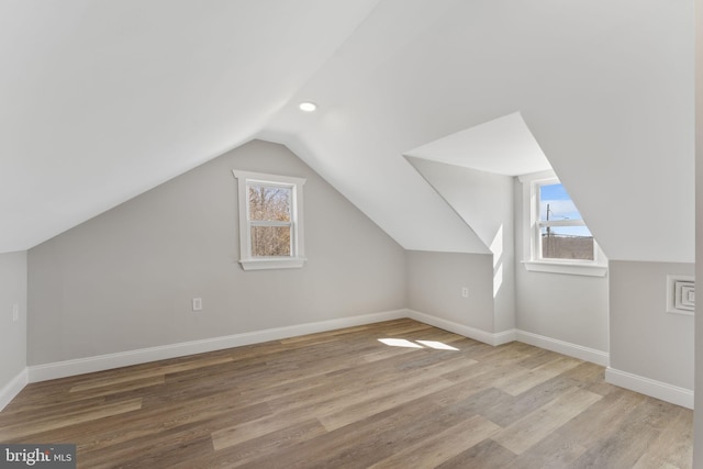 additional living space with lofted ceiling, plenty of natural light, wood finished floors, and baseboards