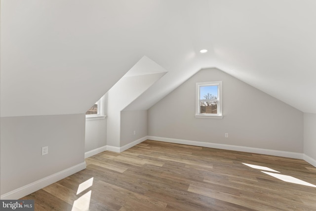 additional living space with baseboards, lofted ceiling, and wood finished floors