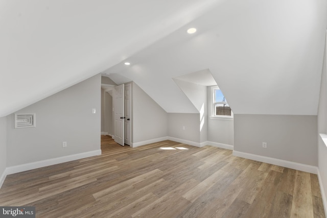 additional living space with light wood-type flooring, baseboards, and lofted ceiling