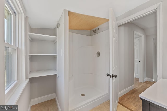 bathroom with a shower stall and baseboards