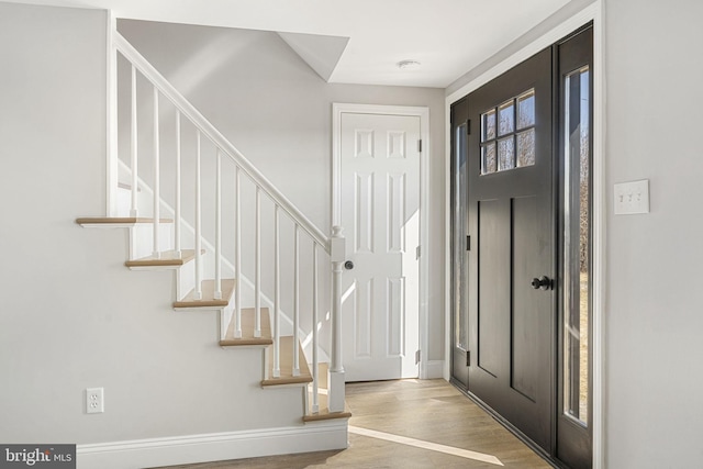 foyer featuring stairs, baseboards, and wood finished floors