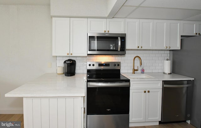 kitchen featuring a sink, backsplash, appliances with stainless steel finishes, and white cabinets