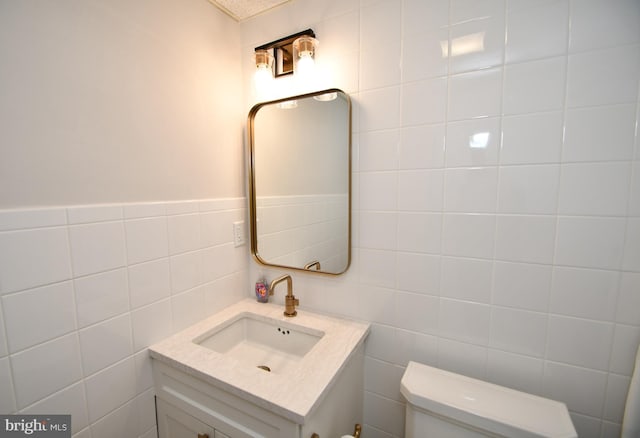 bathroom with vanity, toilet, and tile walls