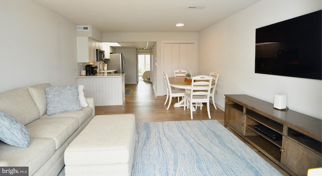 living area featuring visible vents and wood finished floors