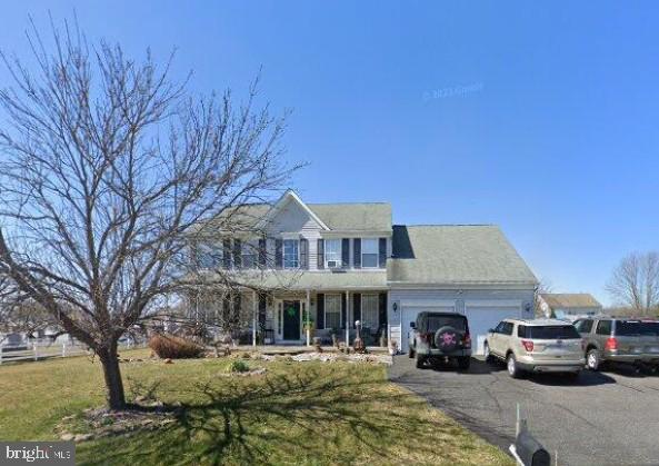 view of front of house with a front lawn, covered porch, a garage, and driveway