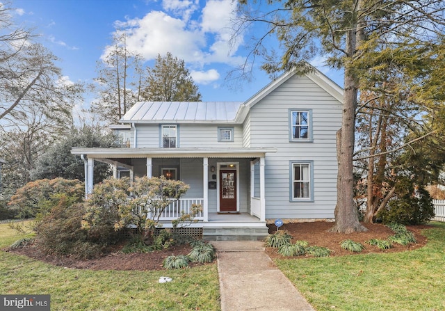 view of front of property featuring a porch, a front lawn, and metal roof