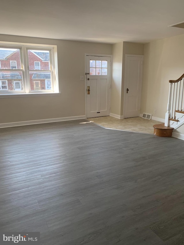 entrance foyer with stairway, baseboards, visible vents, and wood finished floors