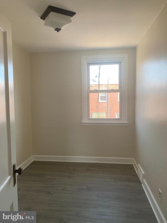 unfurnished room with dark wood finished floors, visible vents, and baseboards