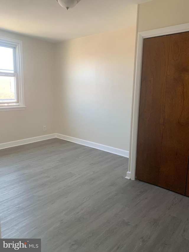 unfurnished bedroom with baseboards and dark wood-type flooring