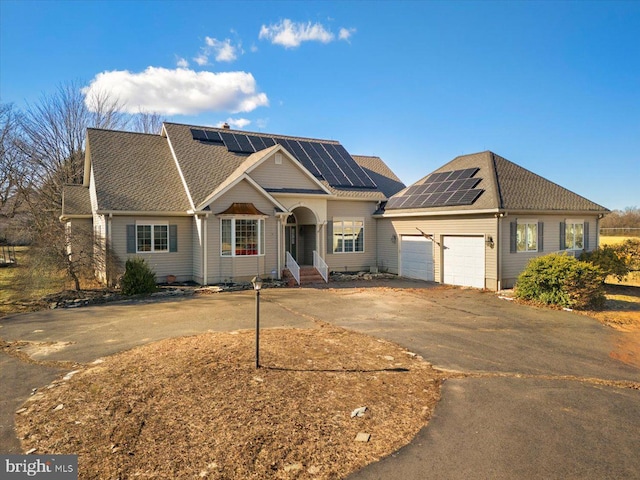 view of front of property featuring solar panels, a shingled roof, entry steps, a garage, and driveway