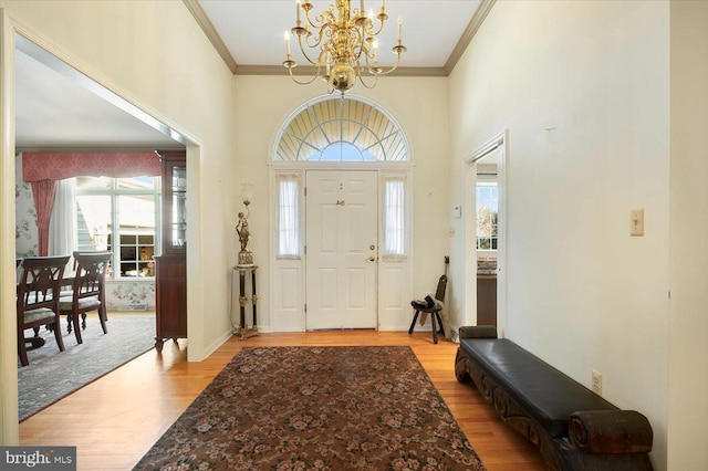 entryway featuring light wood-type flooring, a chandelier, and ornamental molding