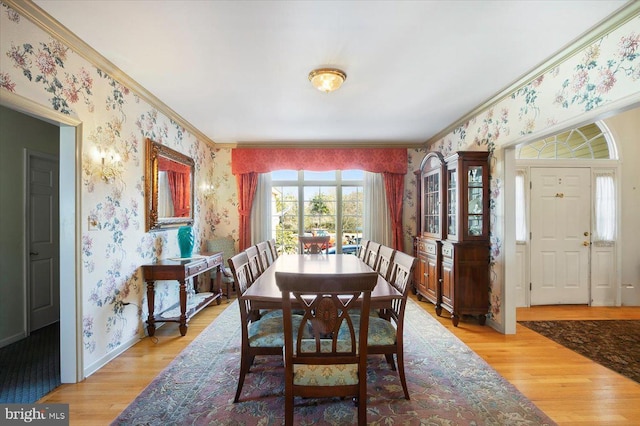 dining space with light wood-type flooring, baseboards, ornamental molding, and wallpapered walls