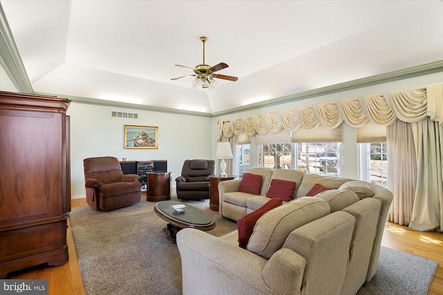 living area with visible vents, light wood-style flooring, a raised ceiling, and ceiling fan