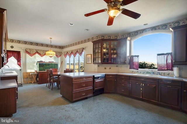 kitchen with carpet floors, a peninsula, light countertops, and a sink