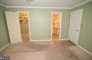 unfurnished bedroom with a closet, a spacious closet, crown molding, and baseboards