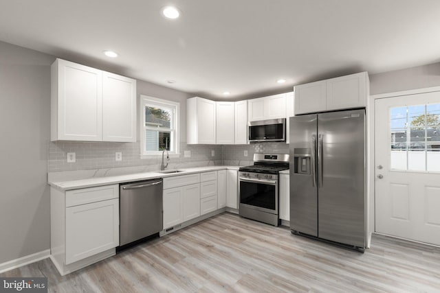 kitchen featuring a sink, light countertops, white cabinets, appliances with stainless steel finishes, and backsplash