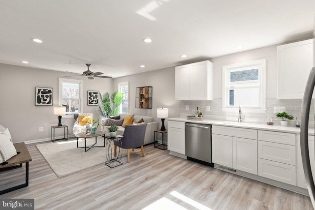 kitchen featuring visible vents, a sink, open floor plan, appliances with stainless steel finishes, and tasteful backsplash