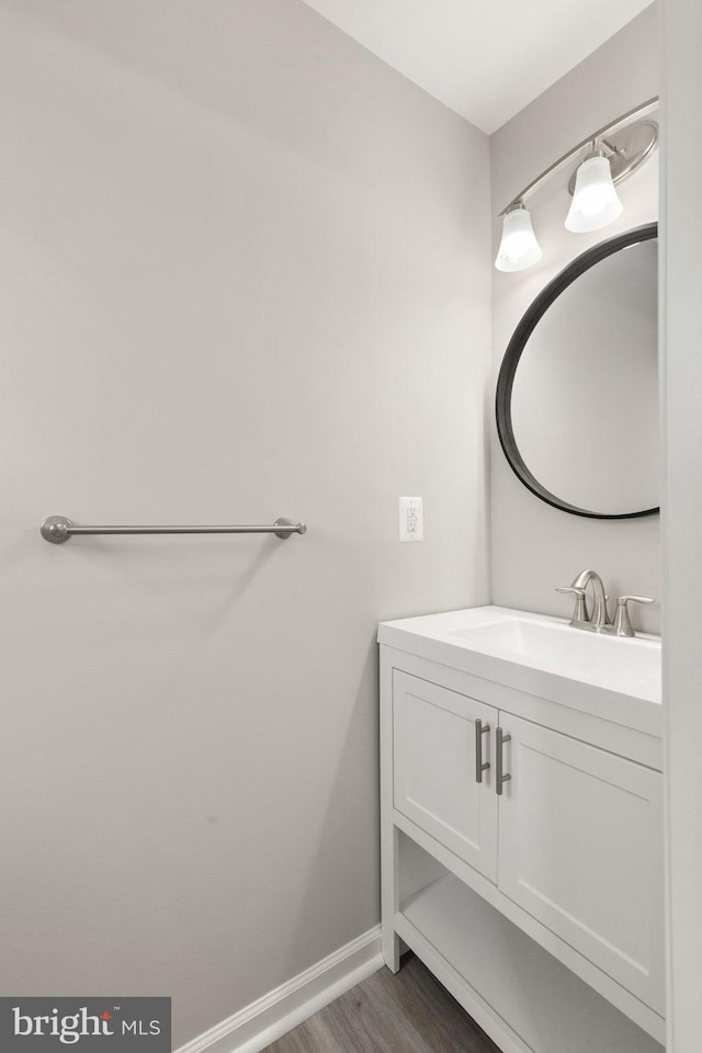 bathroom with baseboards, wood finished floors, and vanity