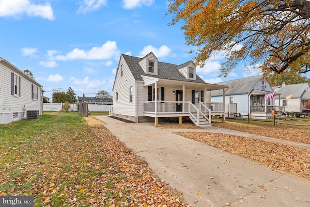 view of front of home with a front yard, fence, a porch, central AC, and concrete driveway