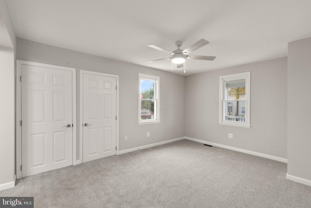 unfurnished bedroom featuring multiple windows, visible vents, and carpet floors