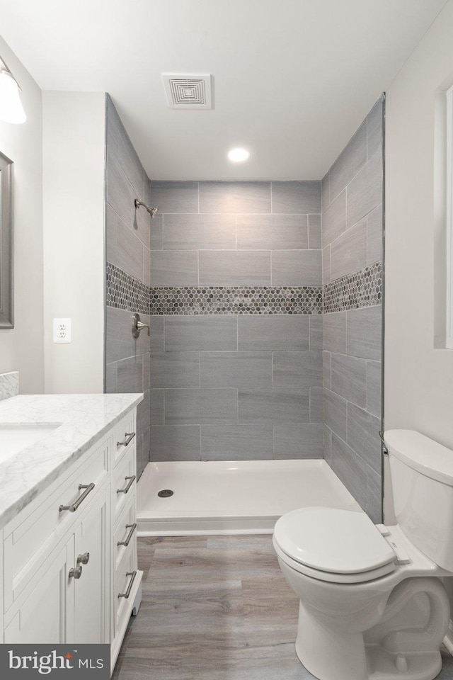 full bathroom with vanity, toilet, visible vents, and tiled shower