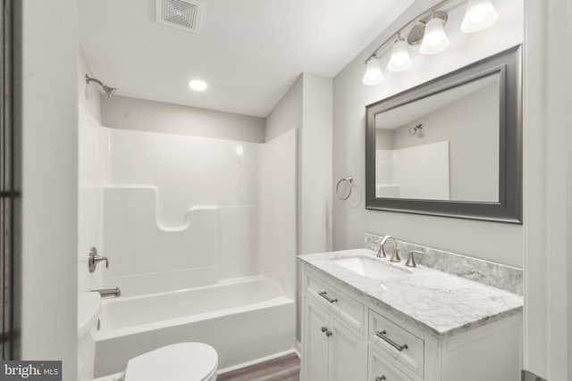 bathroom featuring vanity, wood finished floors, visible vents, bathing tub / shower combination, and toilet