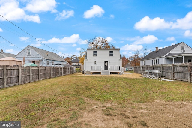 back of property with a yard, a deck, and a fenced backyard