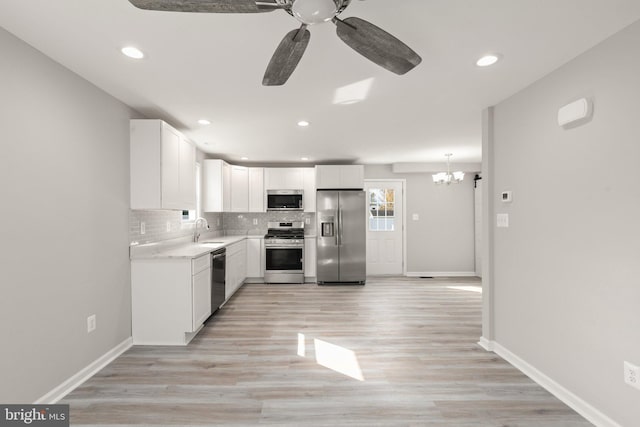 kitchen with light countertops, decorative backsplash, appliances with stainless steel finishes, white cabinets, and a sink