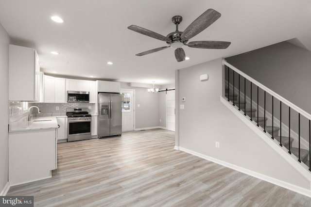 kitchen featuring backsplash, light wood-type flooring, white cabinets, stainless steel appliances, and a sink