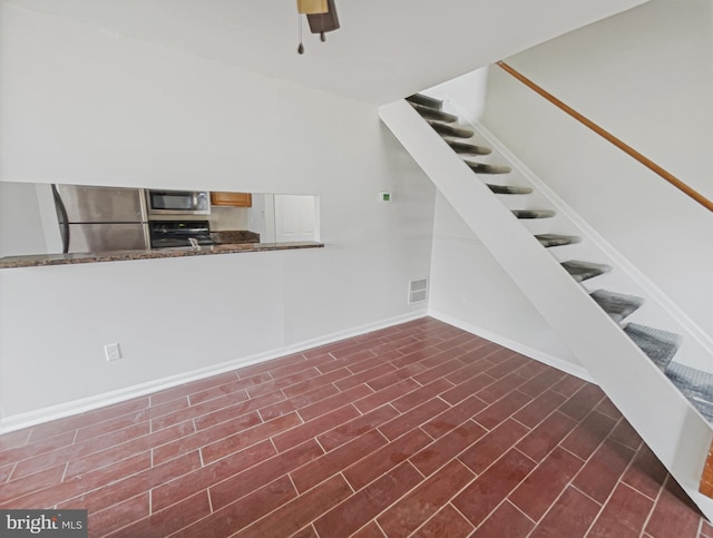 staircase featuring wood finished floors, a ceiling fan, visible vents, and baseboards